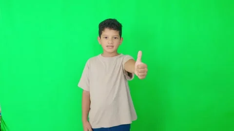 A young boy is standing in front of a green background Stock Footage 312356790
