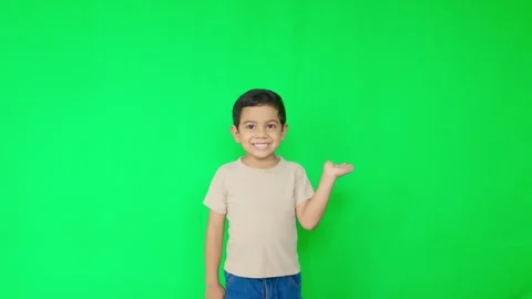 A young boy is standing in front of a green background Stock Footage 312635783
