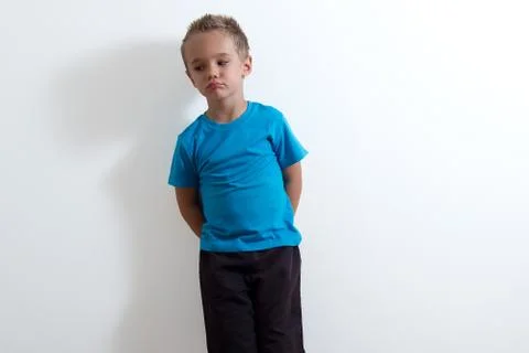 A young boy standing in front of a white wall with a funny face Foto stock