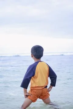 Young boy standing in ocean looking at horizon Stock Photos