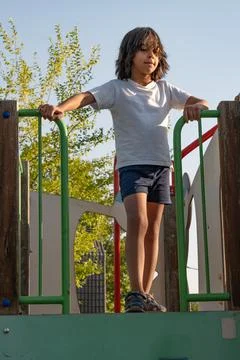 Young boy standing on playground structure enjoying outdoor activities Stock Photos