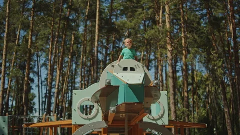 Young boy standing on top of a large spaceship-themed wooden playground Stockbeeldmateriaal 343207857