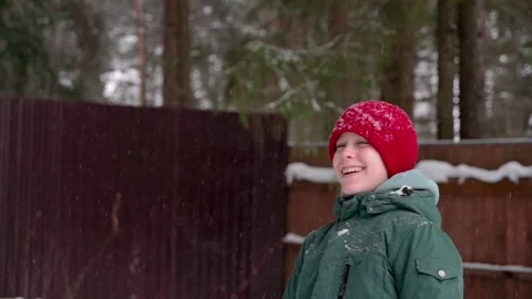 Young boy stands against the backdrop of a winter forest and a fence and laugh Stock Footage 265791347