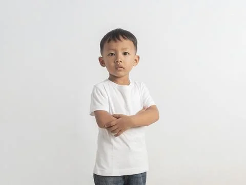 Young boy stands against plain white background. He wears plain white t-shi.. Stock Photos