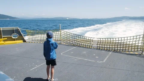 Young boy stands on back of ferry while it cruses through San Juan Islands Stock Footage 100552114