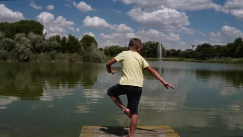 A young boy stands on a dock overlooking a body of water Stock-Footage 314491051