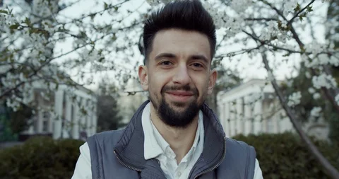 A young boy stands by a flowering tree and looks into the distance Stock Footage 129850871