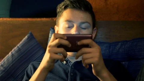 Young boy staring at smartphone sitting in cafe at night Stock Footage 70898676