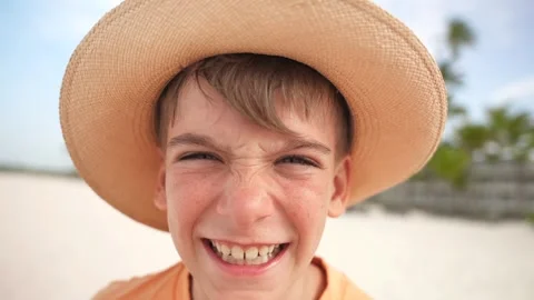 Young boy in straw hat making funny smile faces on the tropical beach on the Stock Footage 279127812