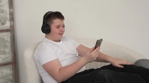 Young boy student wearing headset headphones with phone video call talking Stock Footage 262079514
