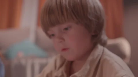 Young boy studies paper on floor holding pencil carefully Видео 324912269