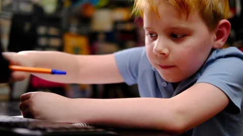 A young boy is studying hard at the table at home. Writes with a pen in a not Vidéo 173066953