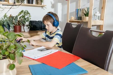 Young boy studying at home using laptop with headphones 스톡 사진