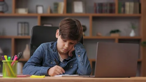 Young boy studying remotely at home using laptop. Sad schoolboy feeling bored Stock Footage 203796416