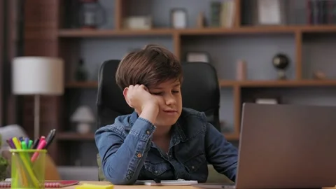 Young boy studying remotely at home using laptop. Tired schoolboy falling asleep Stock Footage 203796418