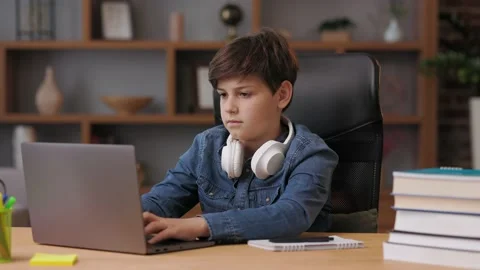 Young boy studying remotely at home using laptop. Cute schoolboy doing homework Stock Footage 213310131