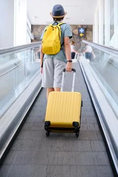 Young boy with suitcase up the escalator. Stock Photos