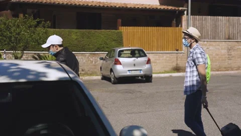 A young boy with a summer hat and suitcase meets and greets his friend, Covid Stock Footage 155249021