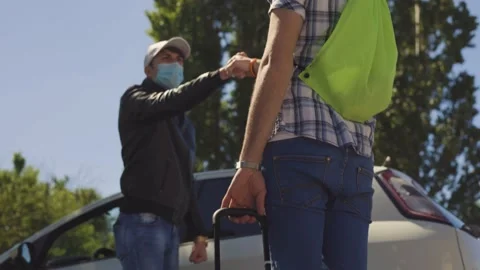 A young boy with a summer hat and suitcase meets and greets his friend, Covid Stock Footage 155249044