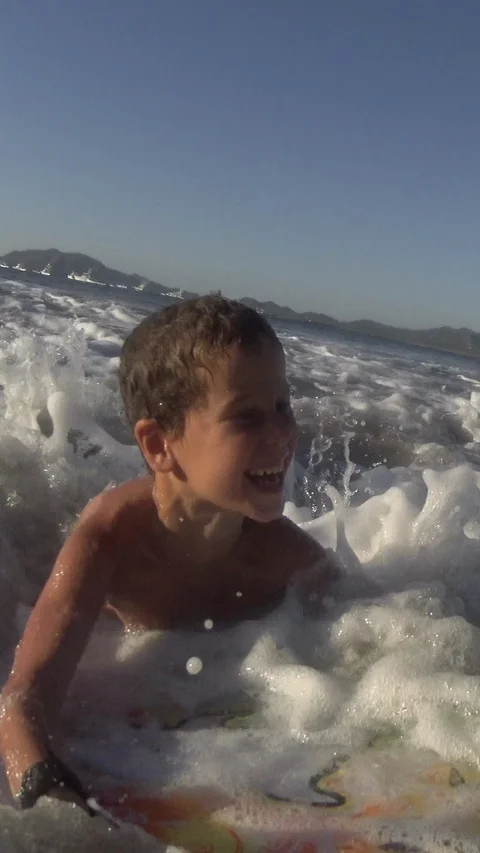 Young Boy surfing jumping waves Body Board at the beach. Vertical, Social Media Stock Footage 121619938