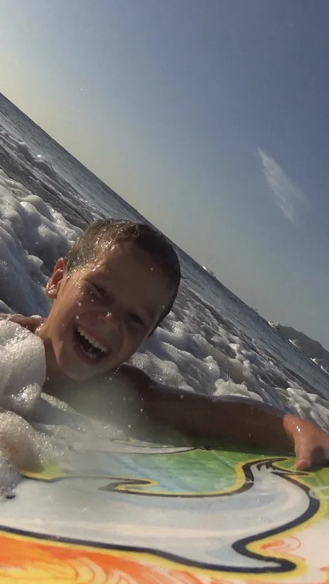 Young Boy surfing jumping waves Body Board at the beach. Vertical, Social Media Video stock 121619996