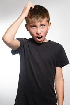 Young boy with surprised expression, hand on head, looking directly at the .. 库存照片