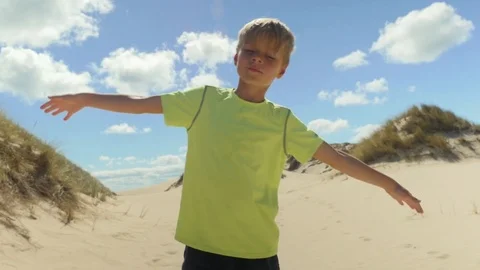 Young boy sways with the wind at the beach Stock Footage 79211990
