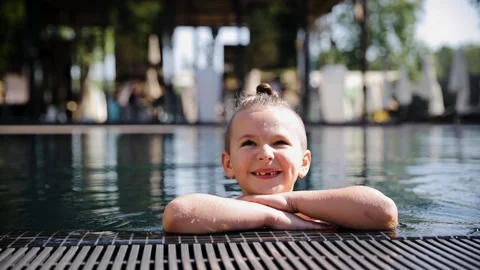 Young boy swiming at the pool. Child in the pool looking at the camera and smile Stock Footage 267284745