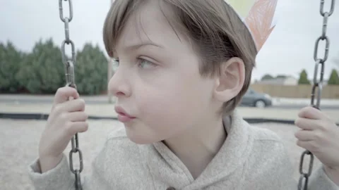 Young boy on swing talks to camera having a conversation. Video stock 169734518