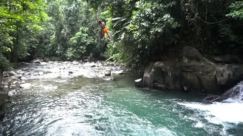 Young Boy Swinging With Rope Into River With Waterfall [Slow Motion] Stock Footage 88884057