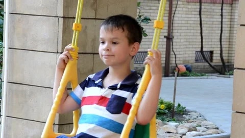 A young boy is swinging set in a park. The small child is having fun Stock Footage 151151874