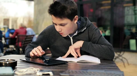 Young boy with tablet computer doing homework in cafe HD Stock Footage 37066315