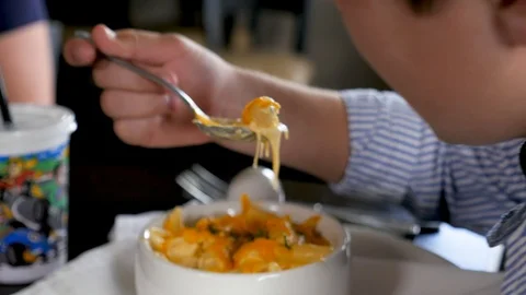 Young boy takes bite of mac and cheese in nice restaurant Stock-Footage 94241581