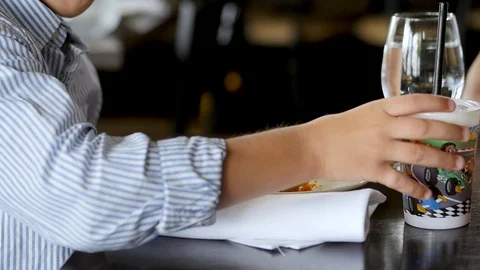 Young boy takes a drink in a nice restaurant Stock Footage 94241552