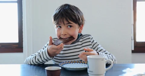 Young boy taking a bite from sliced bread in the morning. Child eating breakf Stock Footage 118239799