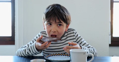 Young boy taking a bite from sliced bread in the morning. Child eating breakf Stock Footage 118239828