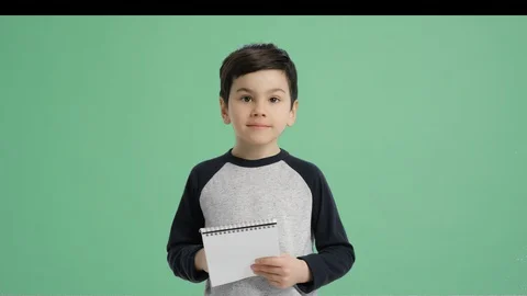 Young boy taking notes and looking at the camera - Alpha Channel, Green screen Stock Footage 129396795