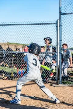 Young boy taking a swing at a baseball with the team defocused in the background Stock Photos