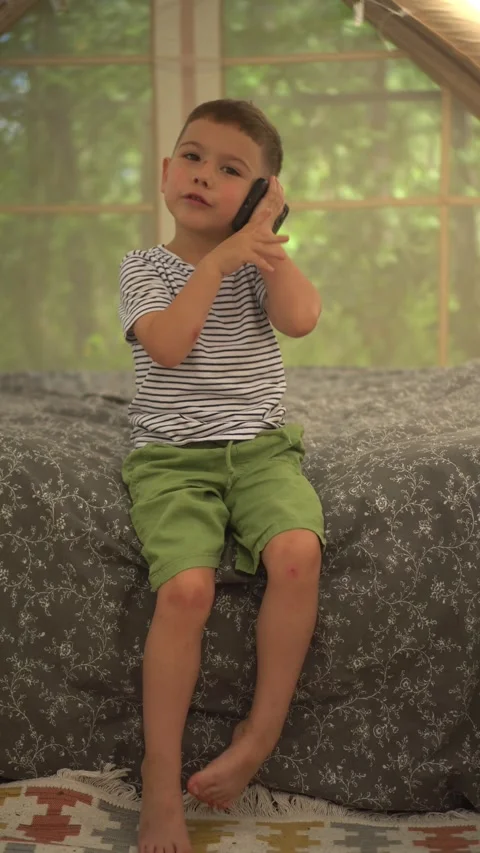Young Boy Talking on the Phone in an Inflatable Tent on the Bed Indoors 스톡 동영상 343894557