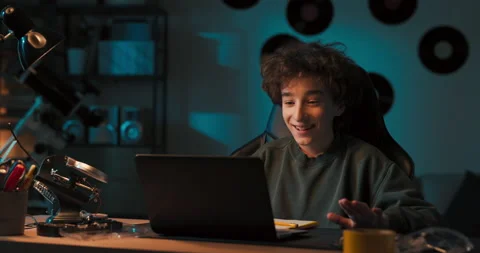 A young boy is talking through laptop camera with a friend. He waves to friend Stockbeeldmateriaal 200871593