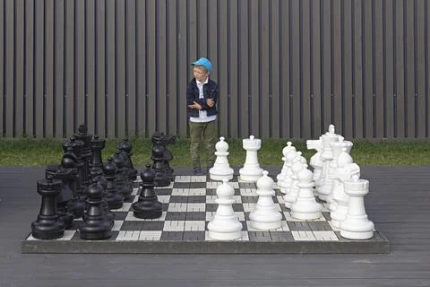 A young boy thinking about the move in chess, big street outdoor chess board Stock Photos
