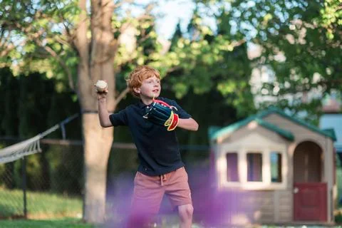 Young boy throws baseball during outdoor backyard play Stock Photos