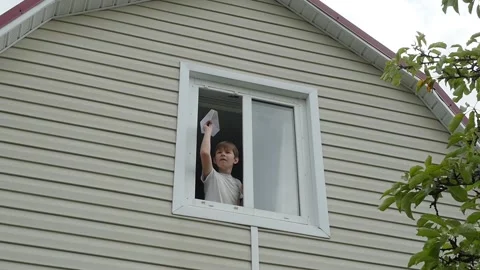 Young boy throws a paper plane out of window, Slow motion Video stock 94903139
