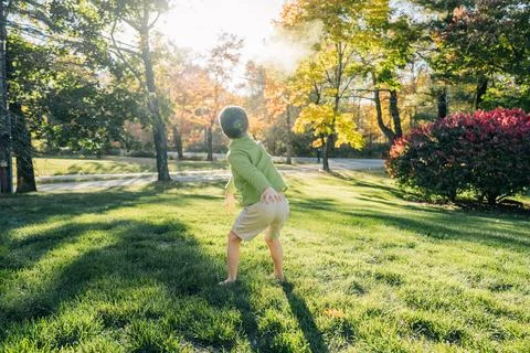 Young boy throws powder in sunny autumn yard scene Stock Photos