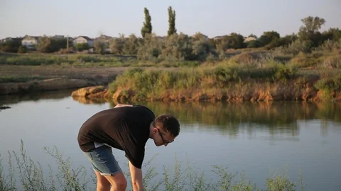 Young boy throws a weed into water, lake 動画素材 94442337