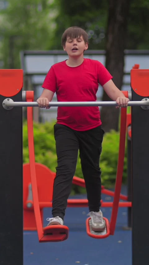 Young Boy Training on Outdoor Playground Bars. Child Fitness Stock Footage 337880004