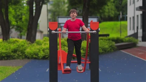 Young Boy Training on Outdoor Playground Bars |Child Fitness Stock Footage 337880021