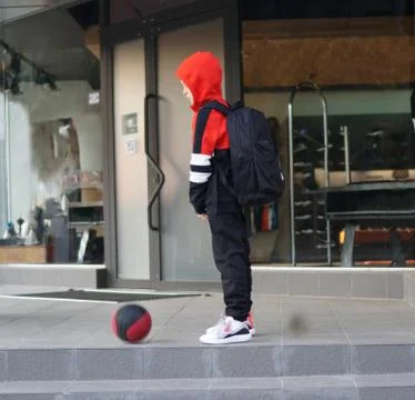 Young boy in training suit posing with basketball in front of store. 스톡 사진