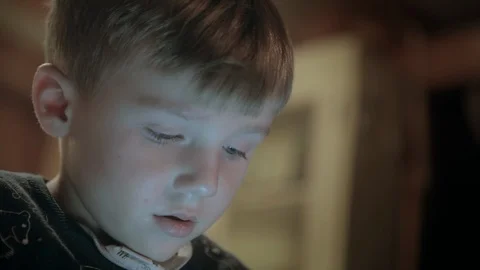 Young boy transfixed looking at a tablet screen, portrait shot with face Stock Footage 101554287
