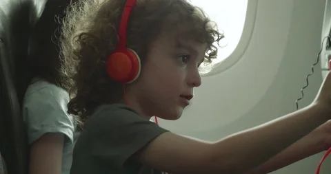 Young boy trying to adjust his seat back entertaiment device on an aeroplane Stock-Footage 107456870